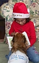 image of child in Santa hat showing her book to her dog